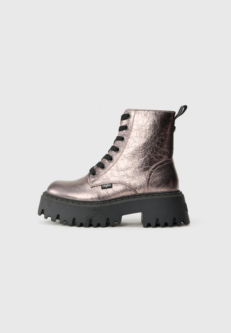Bota de combate de cuero metálico rosa con suela gruesa negra, cordones negros y etiqueta de marca en el costado, sobre un fondo gris claro.