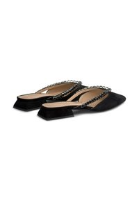 Mule in suede nero con punta affilata e tacco basso a blocco. Presenta due cinturini decorati con accenti metallici sui lati.