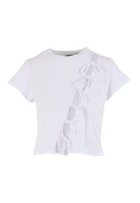 Balta medvilnės trumpa rankovė T-shirt su šoniniu įpjovimu, papuoštu baltomis juostelėmis. Apvalus iškirpimas ir prigludęs dizainas.