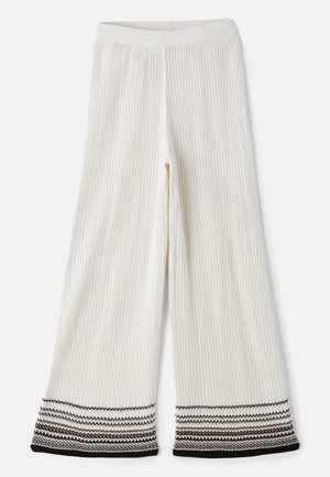 Cream ribbed wide-leg pants with a textured finish. Hem features layered black and white stripes. Elastic waistband for comfortable fit.