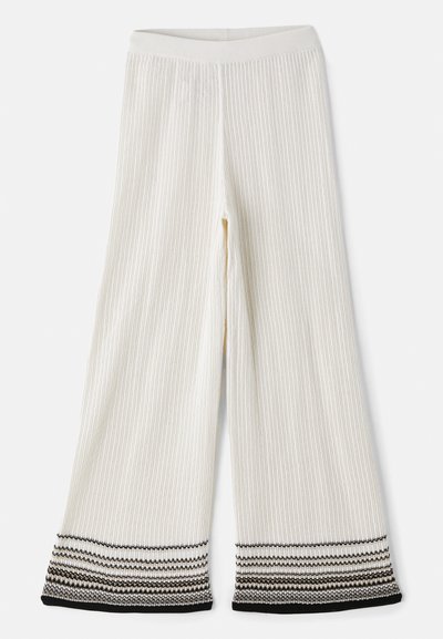 Crème ribgebreide broek met een textuur. De zoom heeft gelaagde zwart-witte strepen. Elastische tailleband voor een comfortabele pasvorm.