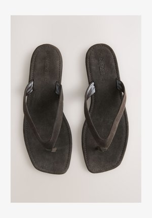 Tongs en daim marron avec une semelle plate, dotées de brides texturées et d'un design simple. Aucun motif ou accent supplémentaire présent.