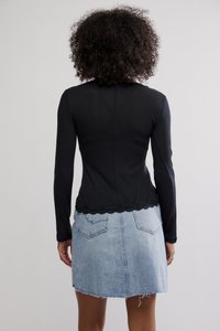 Crni top s dugim rukavima s rebrastom teksturom i čipkanim rubom, uparen s suknjom od svijetloplavog trapera sa izlizanim rubom i stražnjim džepovima.