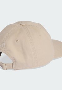 Gorra de béisbol de algodón beige con visera curva, correa ajustable, orificios bordados para ventilación y un acabado de tela texturizada.