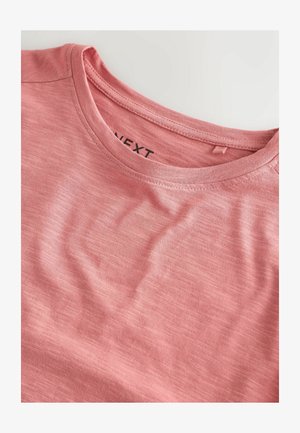 T-shirt rosa chiaro realizzato in tessuto morbido, con scollatura rotonda e una texture sottile. L'etichetta interna riporta la scritta "NEXT".