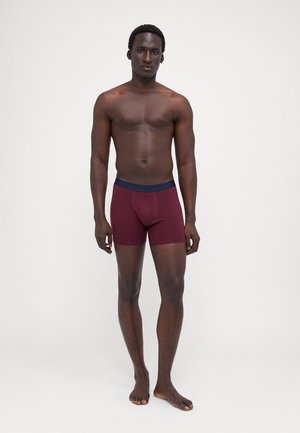 Burgunderfarbene Boxershorts mit einem marineblauen Bund, aus dehnbarem Stoff, in taillierter Passform und mittellanger Länge für Komfort.