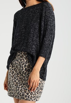 Pull en maille noir avec un décolleté large et des manches trois-quarts, associé à une jupe en imprimé léopard beige montrant sa texture et son motif.