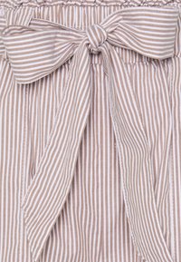 Krémová a béžová pruhovaná látka s texturovaným povrchem, s mašlí v pase a elastickým pasem pro pohodlí.