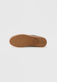 Sole of a brown shoe with textured grip and circular logo near the heel on a plain white background.