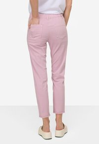 Pantaloni rosa chiaro, elasticizzati con cintura elastica, due tasche posteriori e lunghezza leggermente cropped, abbinati a scarpe con plateau.