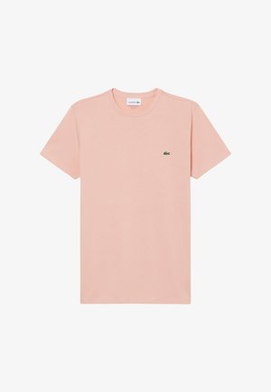 Hellrosa Baumwoll-T-Shirt mit kurzen Ärmeln, rundem Ausschnitt und einem kleinen grünen Lacoste-Logo auf der linken Brust. Schlichtes Design, glatte Textur.