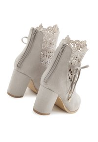 Graue Wildleder-Stiefeletten mit einem Spitzendetail auf der Rückseite, einem dicken Absatz, seitlichen Reißverschlüssen und einer dekorativen Schleife. Die Spitze hat ein florales Muster.