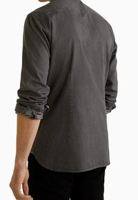 Szara koszula z długim rękawem o luźnym kroju. Ma podwinięte mankiety i prosty dół. Wykonana z miękkiej tkaniny o subtelnej fakturze.