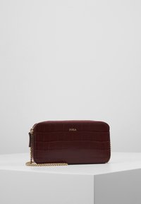 Burgundin nahkainen olkalaukku, jossa on teksturoitu krokotiilikuosi, kultainen ketjukahva ja vetoketjukiinnitys. Etupuolella on logo.