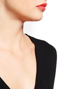 Mustapaita V-kaula-aukolla ja lyhyillä hihoilla, sileä texture, näkyvä kaula-aukko ja pieni mooli kaulalla. Kirkas punainen huulipuna huulilla.