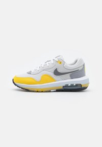 Nike Air Max-sneaker med en övervägande vit, grå och ljusgul färgschema; har andningsbart nät och en synlig luftenhet.
