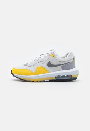 Nike Air Max tenisky s převládající bílou, šedou a jasně žlutou barevnou kombinací; mají prodyšnou síťovinu a viditelnou vzduchovou jednotku.