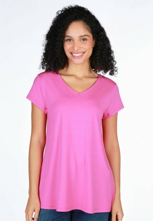 Rosa V-Ausschnitt T-Shirt mit kurzen Ärmeln, glatter Textur, lockerer Passform und einem dezenten Glanz, kombiniert mit blauen Jeans vor einem schlichten Hintergrund.