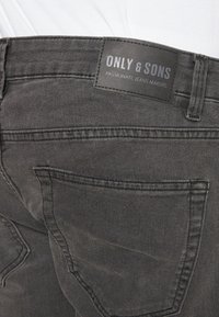 Sorte denim jeans med en matt overflate, med en logo-lapp merket "ONLY & SONS" på livlinen og standard baklommer.