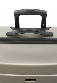 Gray hard-shell suitcase with a textured surface, black retractable handle, zipper closure, and branded hardware at the front.