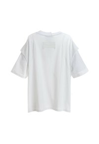 Camiseta blanca de manga corta con cuello redondo y un parche rectangular texturizado en la parte superior de la espalda. Tejido suave con un corte relajado.