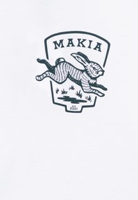 T-shirt blanc avec un graphique noir d'un lapin sautant dans un blason, étiqueté "MAKIA" en haut, et "EST. 2001" en bas.