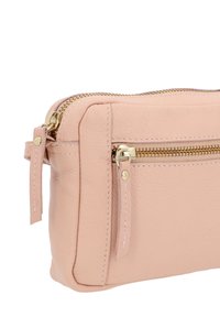 Roze leren cosmetica tas met gouden ritsen en stiksels. Beschikt over een hoofdcompartiment en een voorvak met rits voor extra opbergruimte.