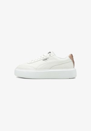 White sneaker with a textured leather upper, lace-up closure, and a prominent platform sole. Features a metallic accent on the heel.