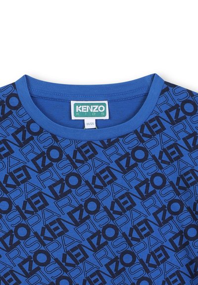T-shirt en coton bleu avec un col rond, arborant un logo "KENZO" noir répété et le texte "PARIS" dans un design à motifs sur l'ensemble du tissu.