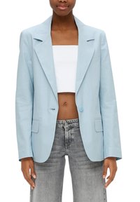 Blazer azzurro chiaro con colletto a rever, chiusura con un bottone e due tasche frontali, abbinato a un top corto bianco e jeans grigi.
