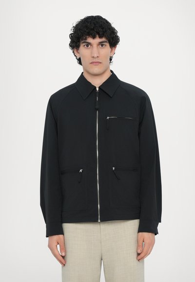 Schwarze Jacke mit einem Reißverschluss vorne, Raglanärmeln und einer Brusttasche. Verfügt über zwei untere Reißverschlusstaschen und ein Kragen-Design. Glatte Textur.