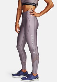Leggings a vita alta, aderenti, di un morbido colore lavanda, con cuciture dettagliate e il logo "Under Armour" in bianco.