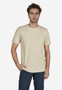 Hellgelbes, gestreiftes T-Shirt mit Rundhalsausschnitt, kurzen Ärmeln und lockerer Passform, kombiniert mit dunkelblauen Hosen. Glatte Textur.