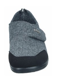 Grey felt slipper with a black rubber sole, rounded shape, and Velcro strap closure. Features a small metallic logo on the side.