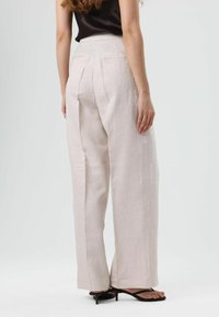 Lichtbeige wijde broek met een gladde textuur, voorzien van twee achterzakken en subtiele plooien bij de taille.