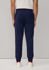 Marineblauwe joggingbroek met elastische tailleband, taps toelopende pijpen en boorden. Heeft een achterzak en zachte, gestructureerde stof.