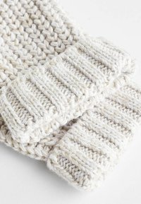 Strickhandschuhe in Off-White, mit einem strukturierten Muster und gerippten Bündchen. Das Material scheint weich und dick zu sein, ideal für Wärme.