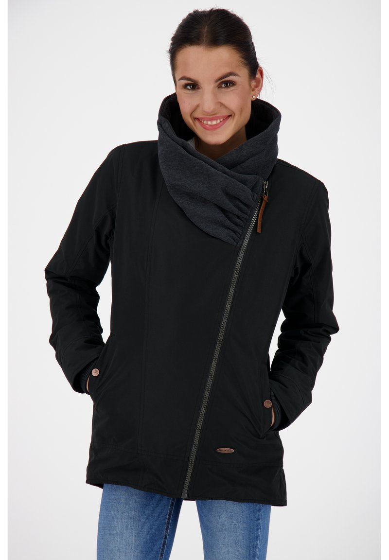 Musta takki vetoketjulla, jossa on suuri harmaa kaulus ja sivutaskut, valmistettu sileästä ja pehmeästä materiaalista. Koristeena ruskeat napit.