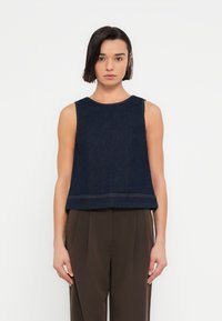 Σκούρο denim τοπ χωρίς μανίκια με στρογγυλή λαιμόκοψη και κοντό κόψιμο, με αντιθετικές ραφές κατά μήκος του τελειώματος. Συνδυάζεται με σκούρο παντελόνι.