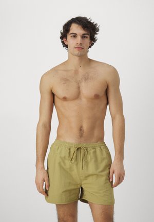 Bañador de hombre en color caqui, hecho de tejido ligero, con cinturilla elástica y cordón ajustable, y bolsillos laterales, con una textura suave.