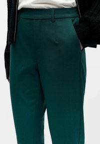 Teal trousers made of smooth fabric, featuring a tailored fit, side pockets, and belt loops, with a plain design and slim cut.