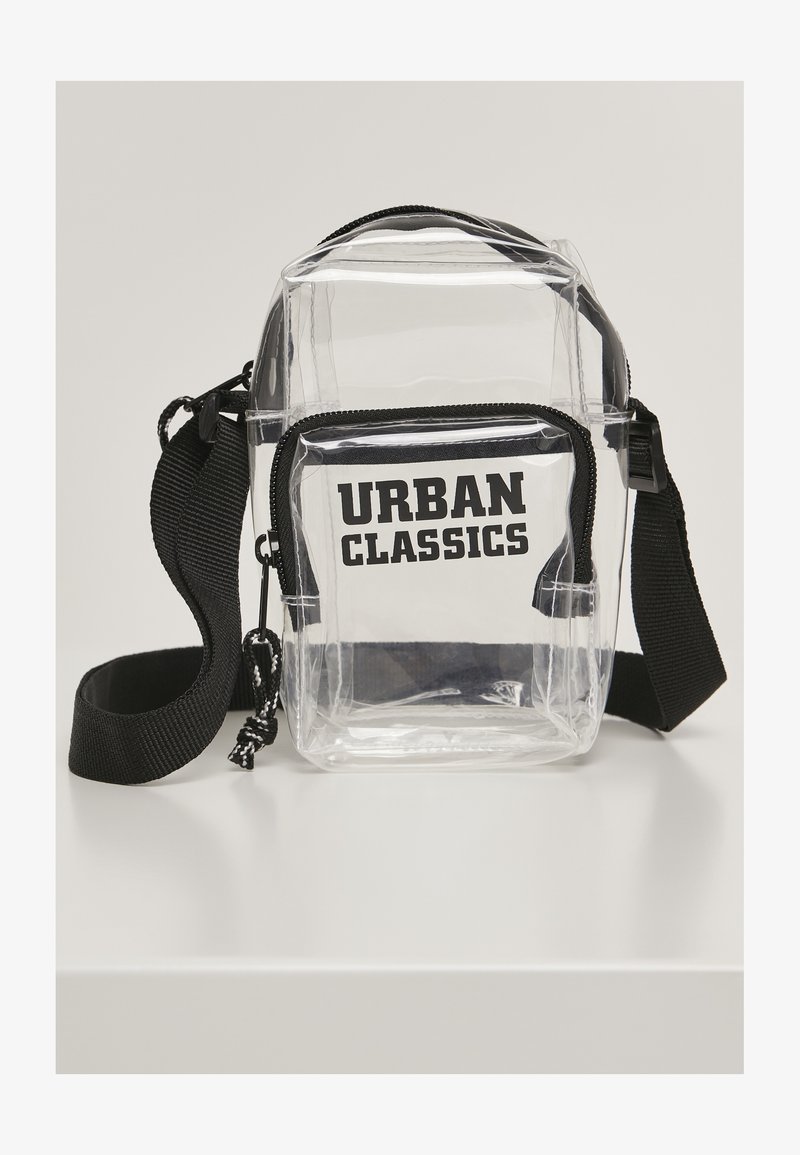 Clear crossbody bag with black accents, zip closure, and "URBAN CLASSICS" printed in bold black text on the front. Adjustable strap included.