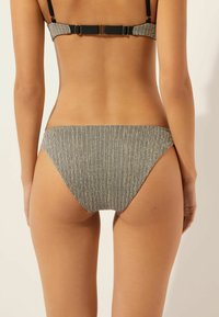 Dół od bikini w paski z wąskimi, czarno-białymi, pionowymi liniami, bezszwowe wykończenia i niskim stanem. Materiał wygląda na gładki.