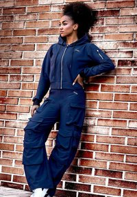 Marinblå zip-up hoodies med stora frontfickor, som matchas med cargo-byxor med flera fickor och en avslappnad passform.
