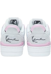 Vita och grå sneakers med rosa detaljer, texturerad mockahäl, präglad logga i svart, platt vit sula och signatur på baksidan.