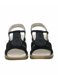 Sandali neri in suede con punta aperta, cinturino intrecciato e dettagli a perle circolari sul davanti. Suola piatta con una soletta di colore chiaro.