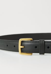 Zwarte leren riem met een gladde textuur, voorzien van een gouden metalen gesp en meerdere gaatjes voor maatverstelling.