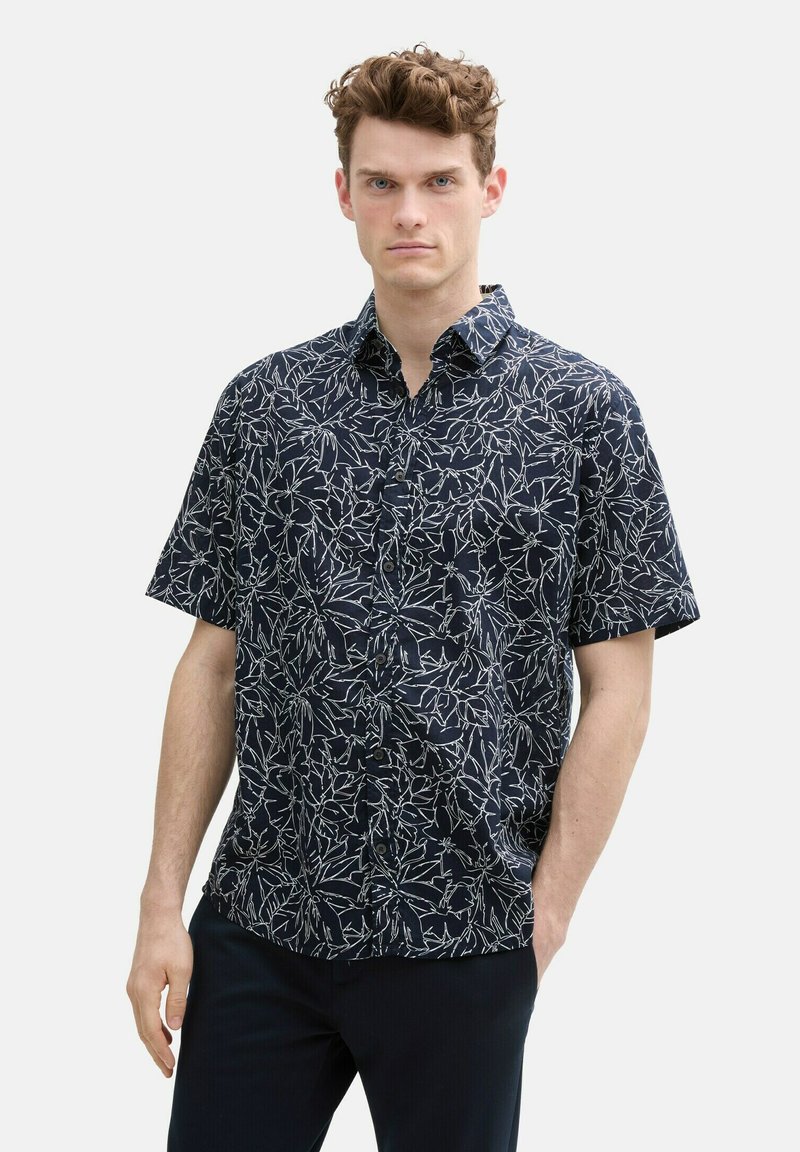 Chemise à manches courtes de couleur bleu marine foncé avec un motif floral blanc, à col et avec fermeture à bouton, fabriquée en tissu léger.
