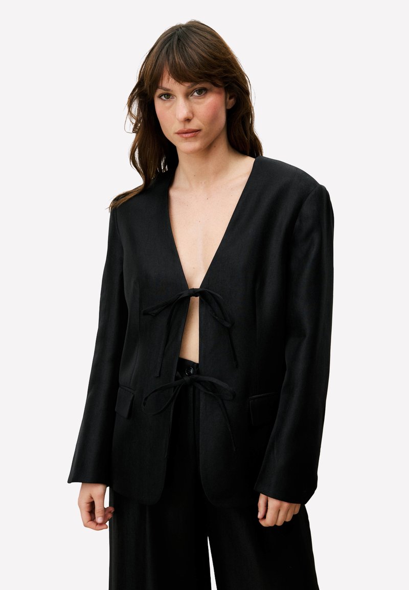 Zwarte blazer met een diepe V-hals en strikjes aan de voorkant. Gemaakt van een gladde stof, met vier zakken en een gestructureerde vorm.