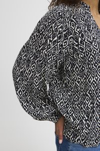 Blusa a maniche larghe in bianco e nero con scollatura a V e forme geometriche a rombo. Tessuto leggero, texture fluida.